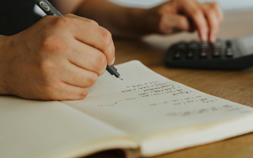 Food costs worked out by hand beside a calculator